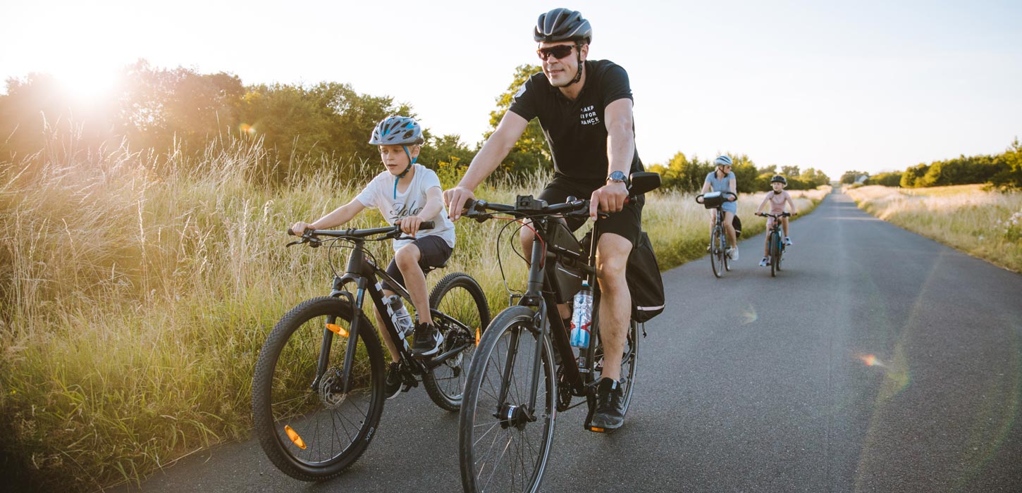 Cyklende familie på lang lige landevej på Kær Halvø