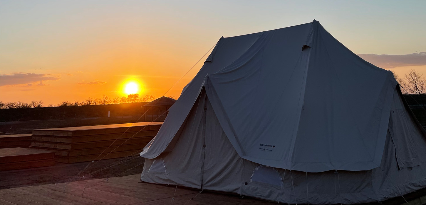 Glampingtelt på Marsk Camp med solnedgang i baggrunden