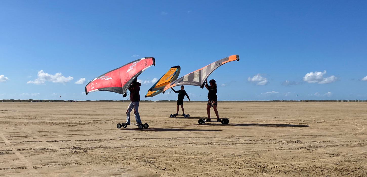 Tre personer kører med Kitewings på Sønderstrand, Rømø
