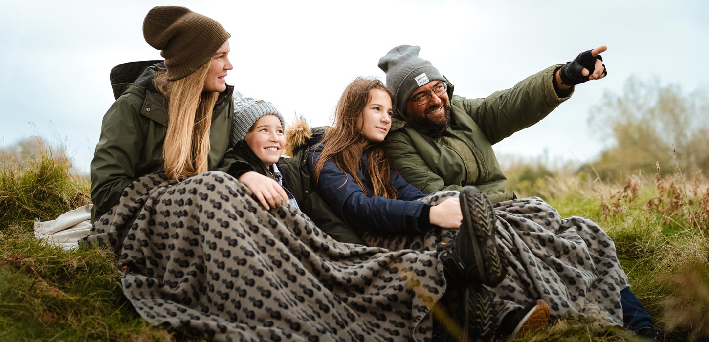 Efterår: familie sidder i klitterne med MOJN tæppe omkring sig