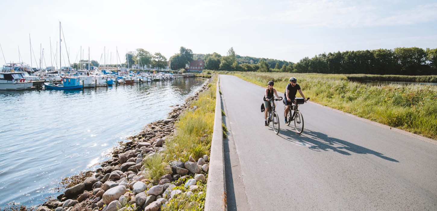 Ein Pärchen fährt Fahrrad über dem Damm von Kalvø