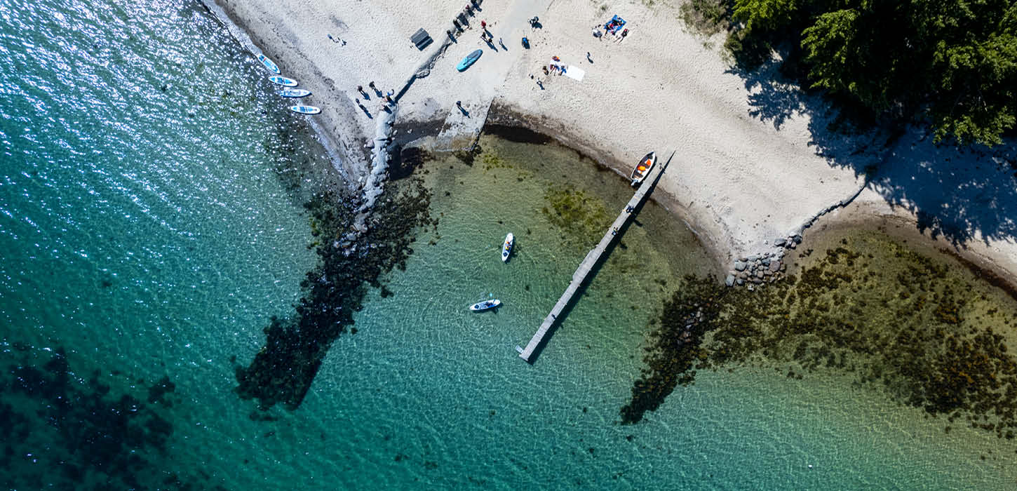 Droneskud af strand, med to SUP boards i vandet