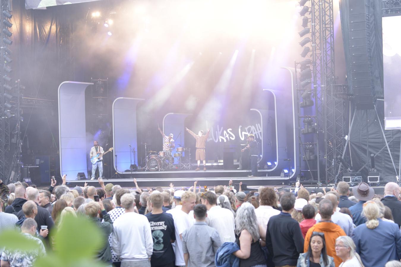 Publikum står foran scenen og nyder koncerten.