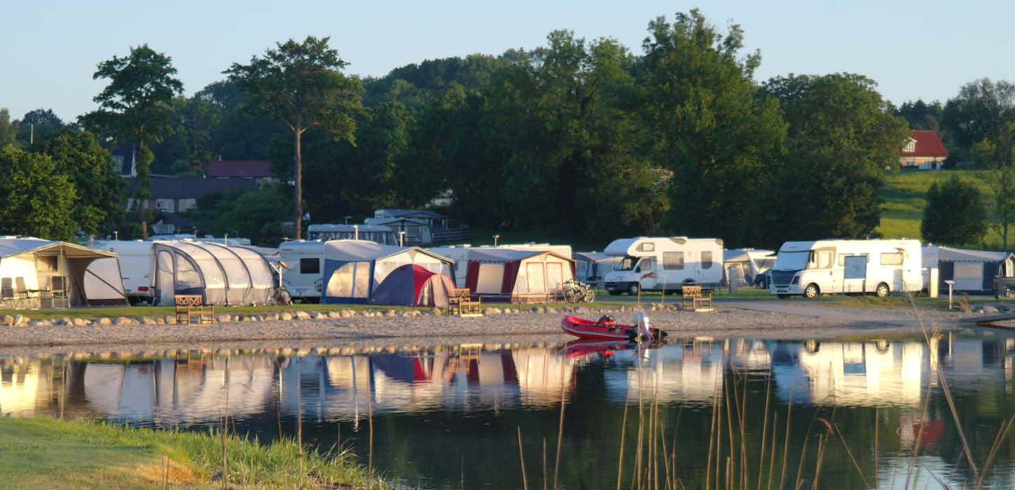 Campingvogne der spejler sig i vandet ved Lærkelunden Camping