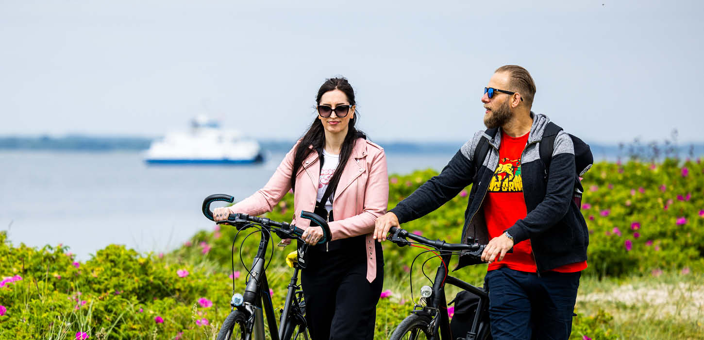 Kvinde og mand på cykelferie på Årø med færge i baggrund
