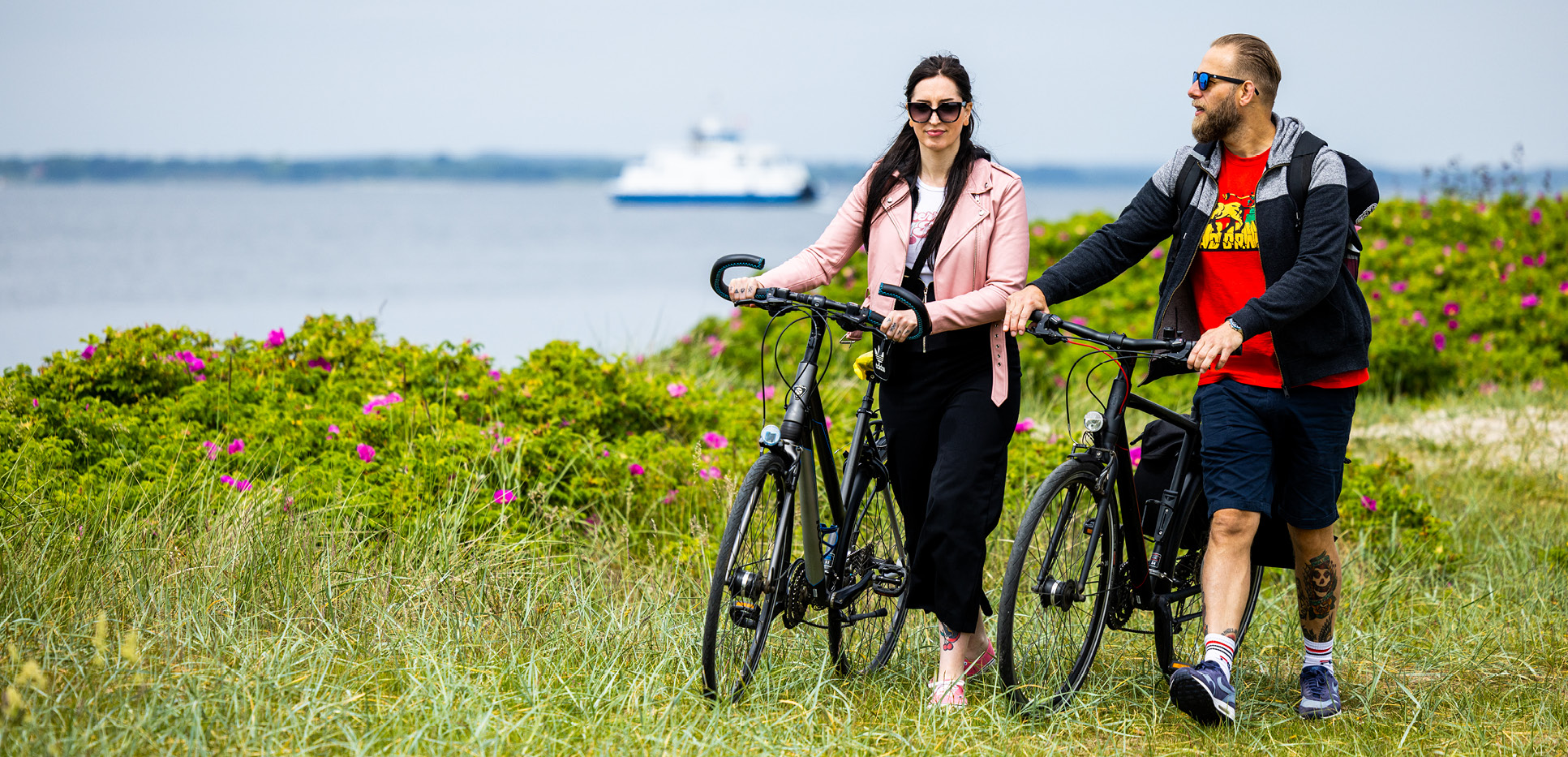 Par med cykler på Aarø og med Aarøfærgen i baggrunden