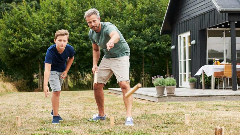 Far og søn spiller Kongespil foran sommerhus