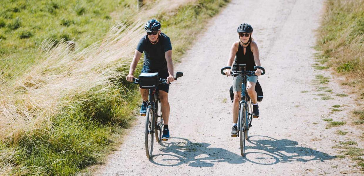 Couple cycling on gravel track on Aarø
