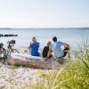 Family sitting next to their bikes on the beach and looking out over the water