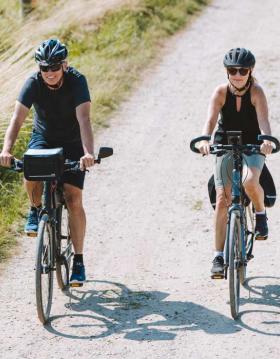 Couple cycling on gravel track on Aarø