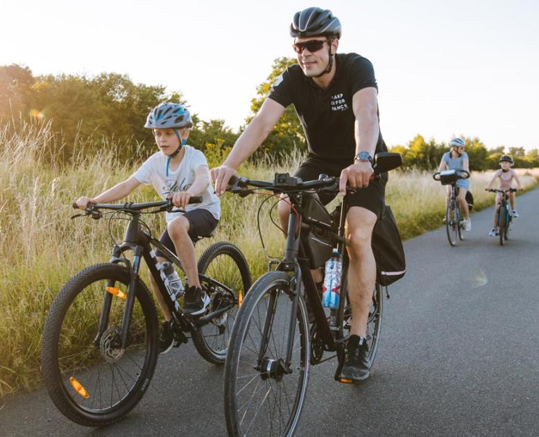 Cycling family on long, straight country road on Kær Halvø